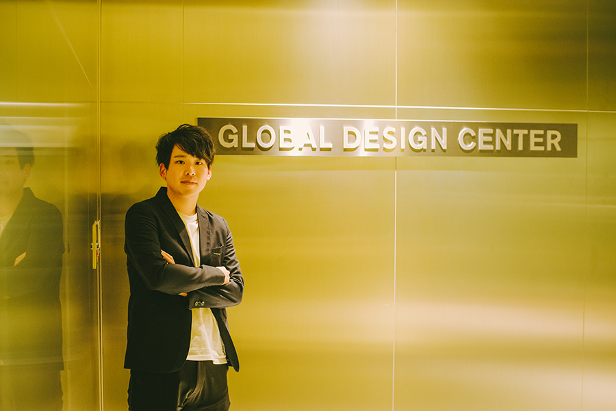 日産自動車株式会社のカーデザイナー・阿部真也さん GLOBAL DESIGN CENTER 入口サインの前で