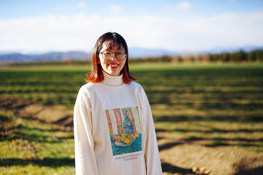 酪農アーティスト、版画家 下山明花さん 広大な牧草地を背景に